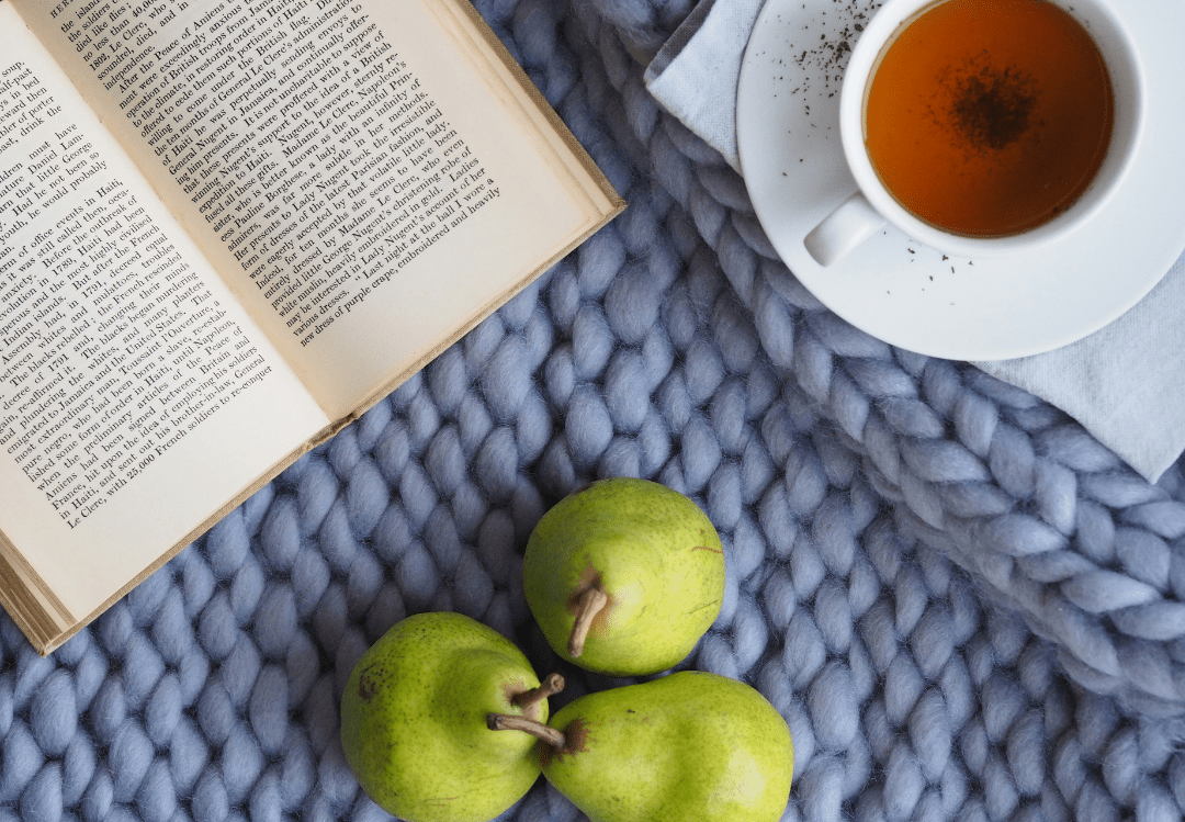 des pommes un thé et un livre sur une table